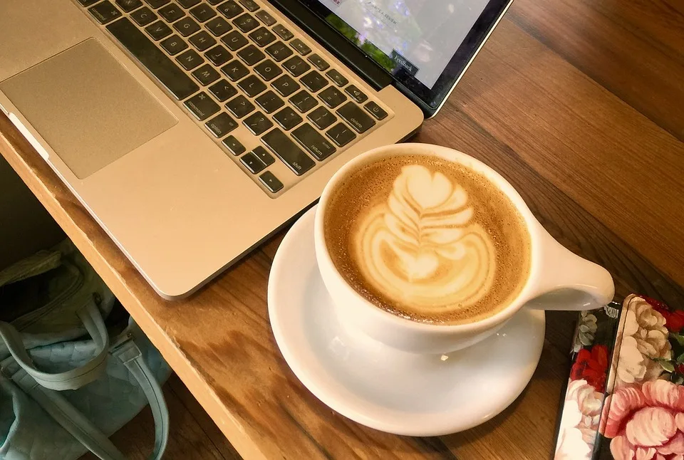 A cup of coffee along with laptop placed on the table