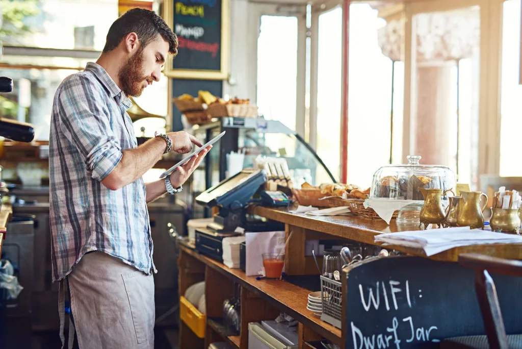  am man checking cafe inventory on tab